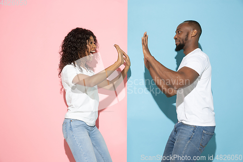 Image of Young emotional man and woman on pink and blue background