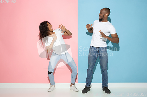 Image of Young emotional man and woman on pink and blue background