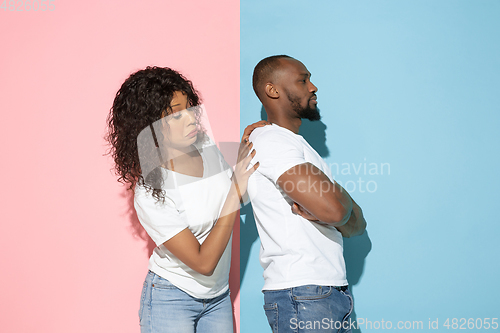 Image of Young emotional man and woman on pink and blue background