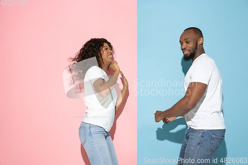 Image of Young emotional man and woman on pink and blue background