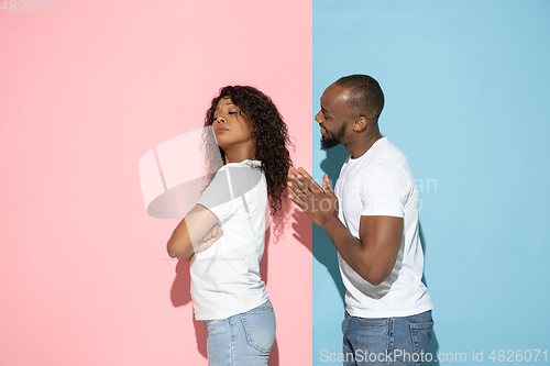 Image of Young emotional man and woman on pink and blue background