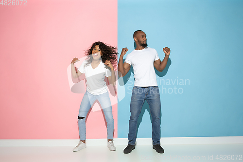 Image of Young emotional man and woman on pink and blue background