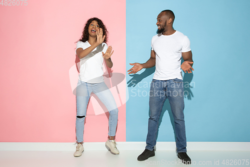 Image of Young emotional man and woman on pink and blue background