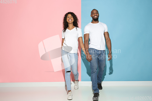 Image of Young emotional man and woman on pink and blue background