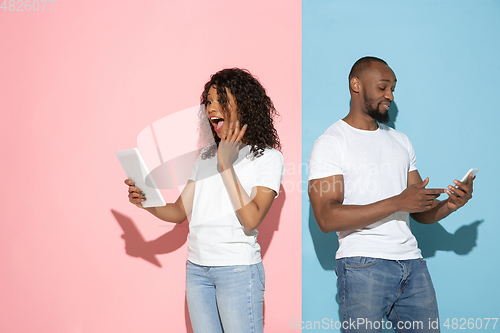 Image of Young emotional man and woman on pink and blue background