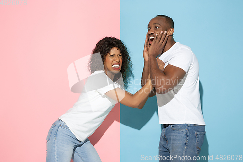 Image of Young emotional man and woman on pink and blue background