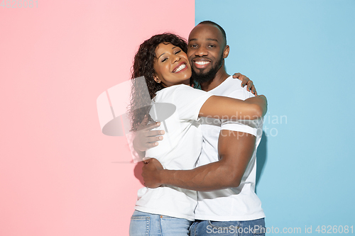 Image of Young emotional man and woman on pink and blue background