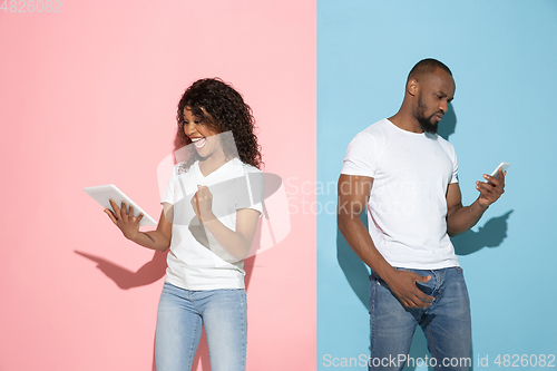 Image of Young emotional man and woman on pink and blue background