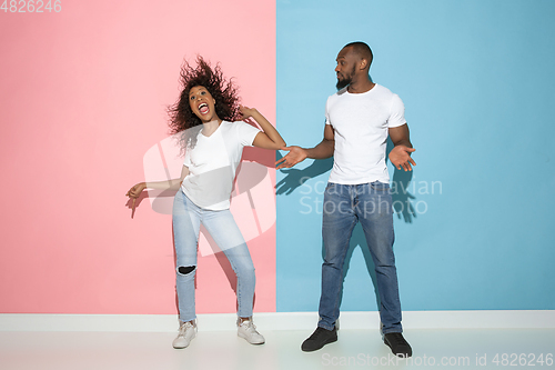 Image of Young emotional man and woman on pink and blue background