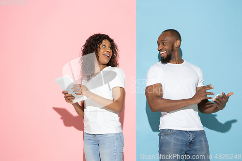 Image of Young emotional man and woman on pink and blue background