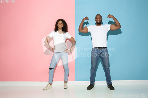 Image of Young emotional man and woman on pink and blue background