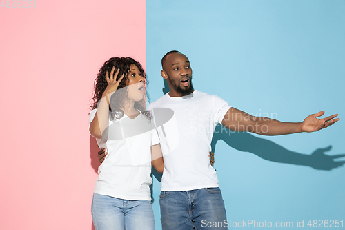 Image of Young emotional man and woman on pink and blue background