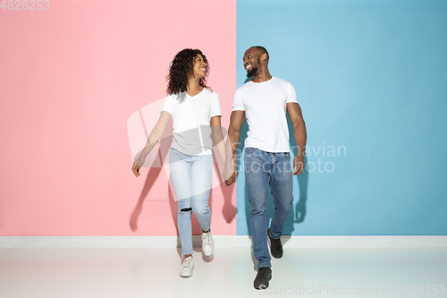 Image of Young emotional man and woman on pink and blue background