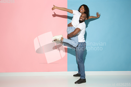 Image of Young emotional man and woman on pink and blue background