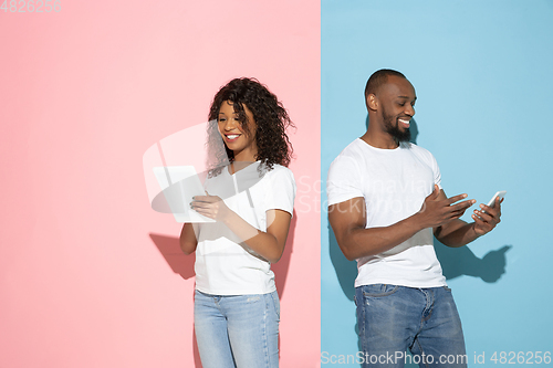 Image of Young emotional man and woman on pink and blue background