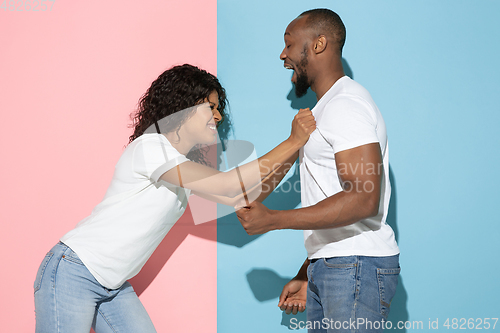Image of Young emotional man and woman on pink and blue background