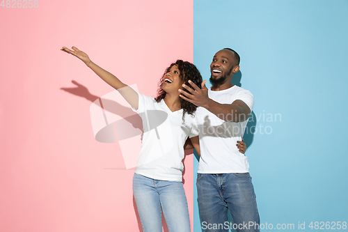Image of Young emotional man and woman on pink and blue background