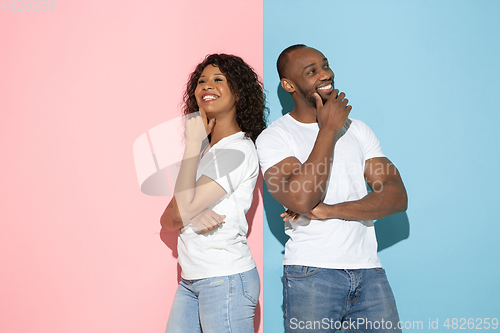 Image of Young emotional man and woman on pink and blue background