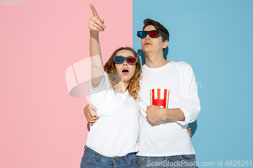 Image of Young emotional man and woman on pink and blue background