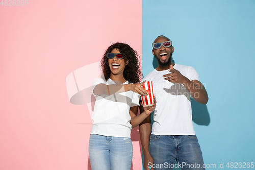 Image of Young emotional man and woman on pink and blue background