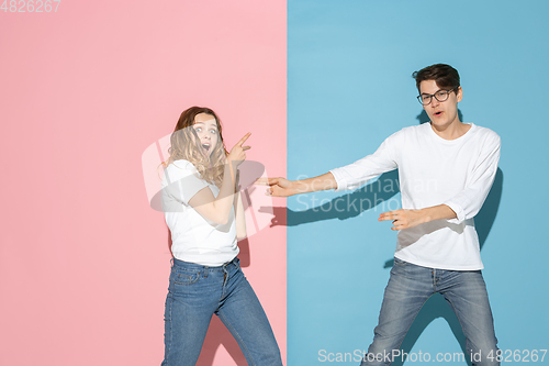 Image of Young emotional man and woman on pink and blue background