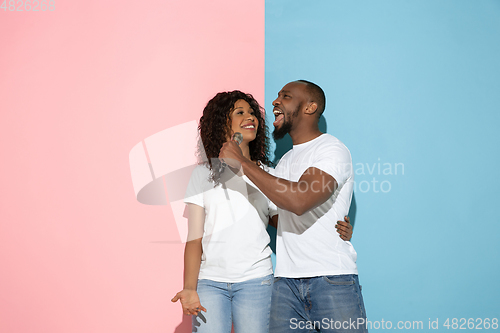 Image of Young emotional man and woman on pink and blue background