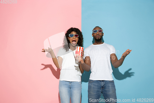 Image of Young emotional man and woman on pink and blue background