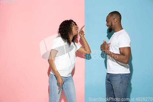 Image of Young emotional man and woman on pink and blue background