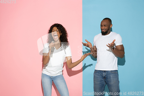 Image of Young emotional man and woman on pink and blue background