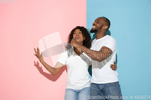 Image of Young emotional man and woman on pink and blue background