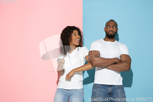 Image of Young emotional man and woman on pink and blue background