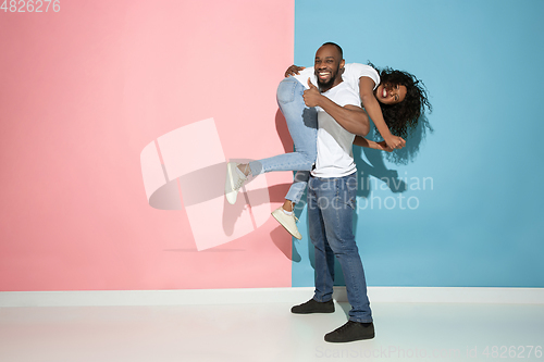 Image of Young emotional man and woman on pink and blue background