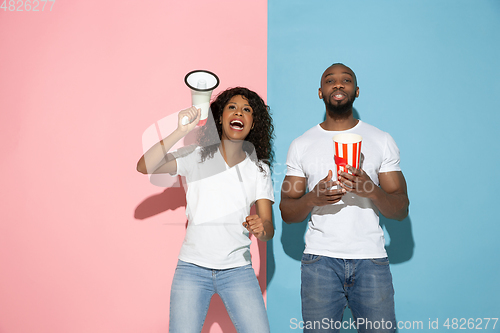 Image of Young emotional man and woman on pink and blue background