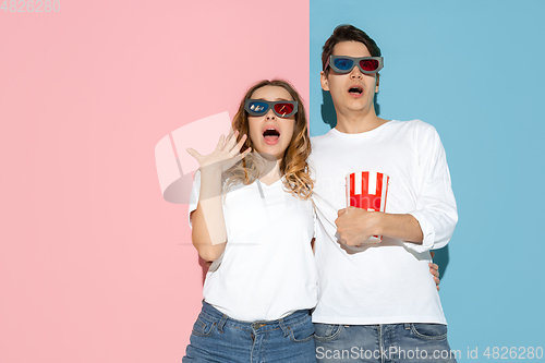 Image of Young emotional man and woman on pink and blue background