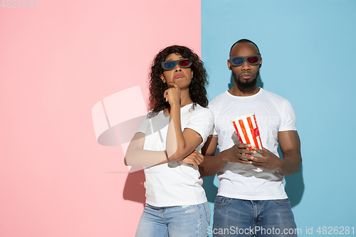 Image of Young emotional man and woman on pink and blue background
