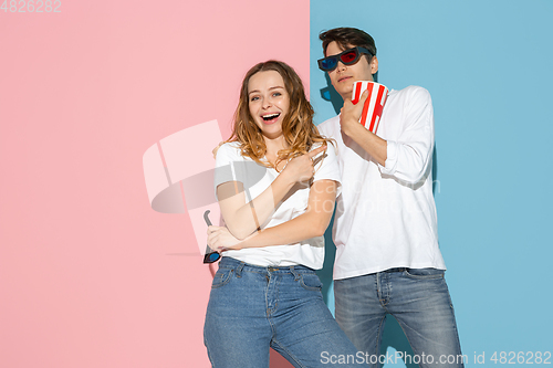 Image of Young emotional man and woman on pink and blue background