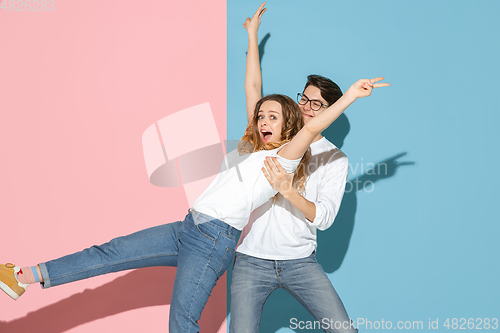 Image of Young emotional man and woman on pink and blue background