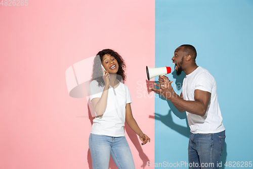 Image of Young emotional man and woman on pink and blue background