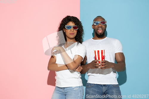 Image of Young emotional man and woman on pink and blue background