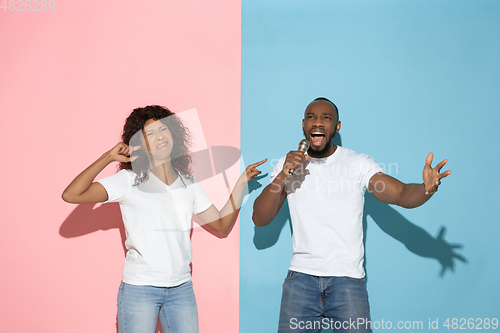 Image of Young emotional man and woman on pink and blue background