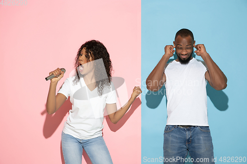 Image of Young emotional man and woman on pink and blue background