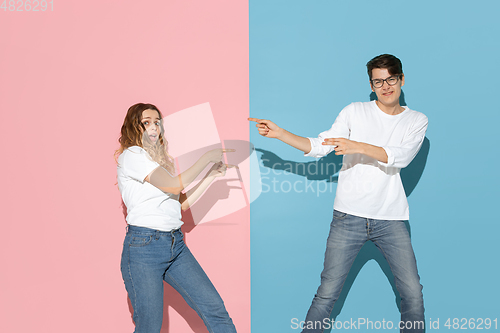 Image of Young emotional man and woman on pink and blue background