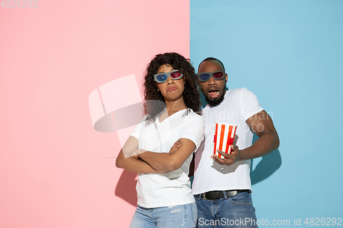 Image of Young emotional man and woman on pink and blue background