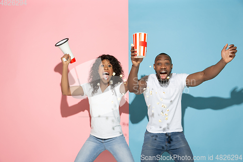 Image of Young emotional man and woman on pink and blue background