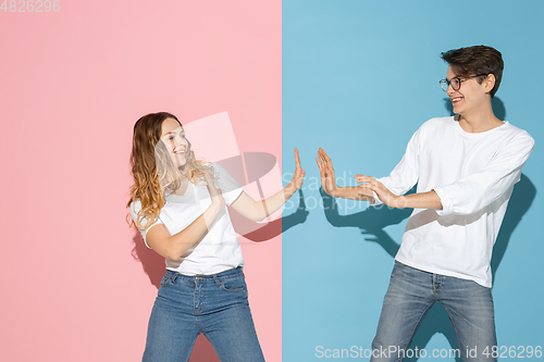 Image of Young emotional man and woman on pink and blue background
