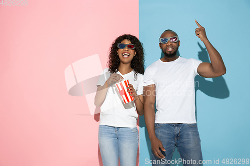 Image of Young emotional man and woman on pink and blue background