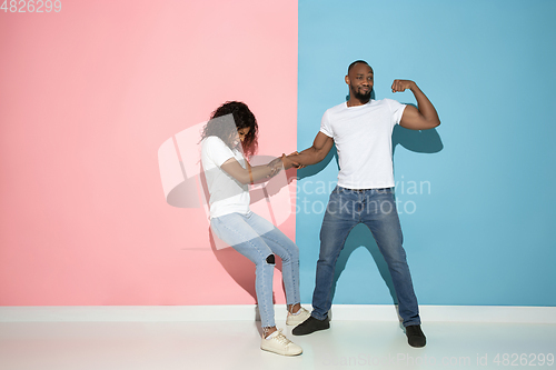 Image of Young emotional man and woman on pink and blue background