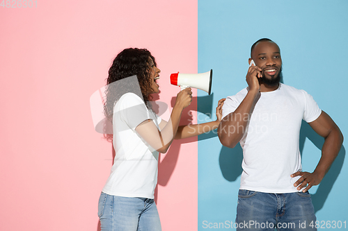 Image of Young emotional man and woman on pink and blue background