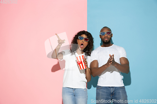 Image of Young emotional man and woman on pink and blue background