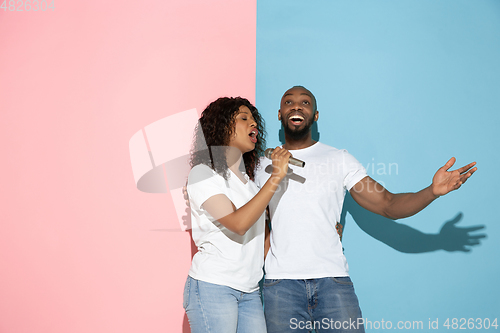 Image of Young emotional man and woman on pink and blue background